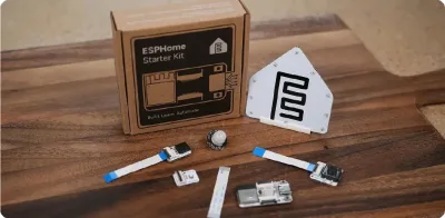 The ESPHome Starter Kit box with its house-shaped board, sensor modules and ribbon cables on a wooden table